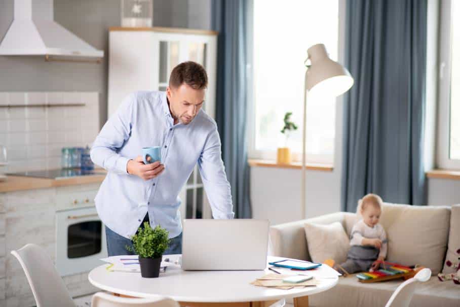 Dad working from home at a laptop while child is playing in the background